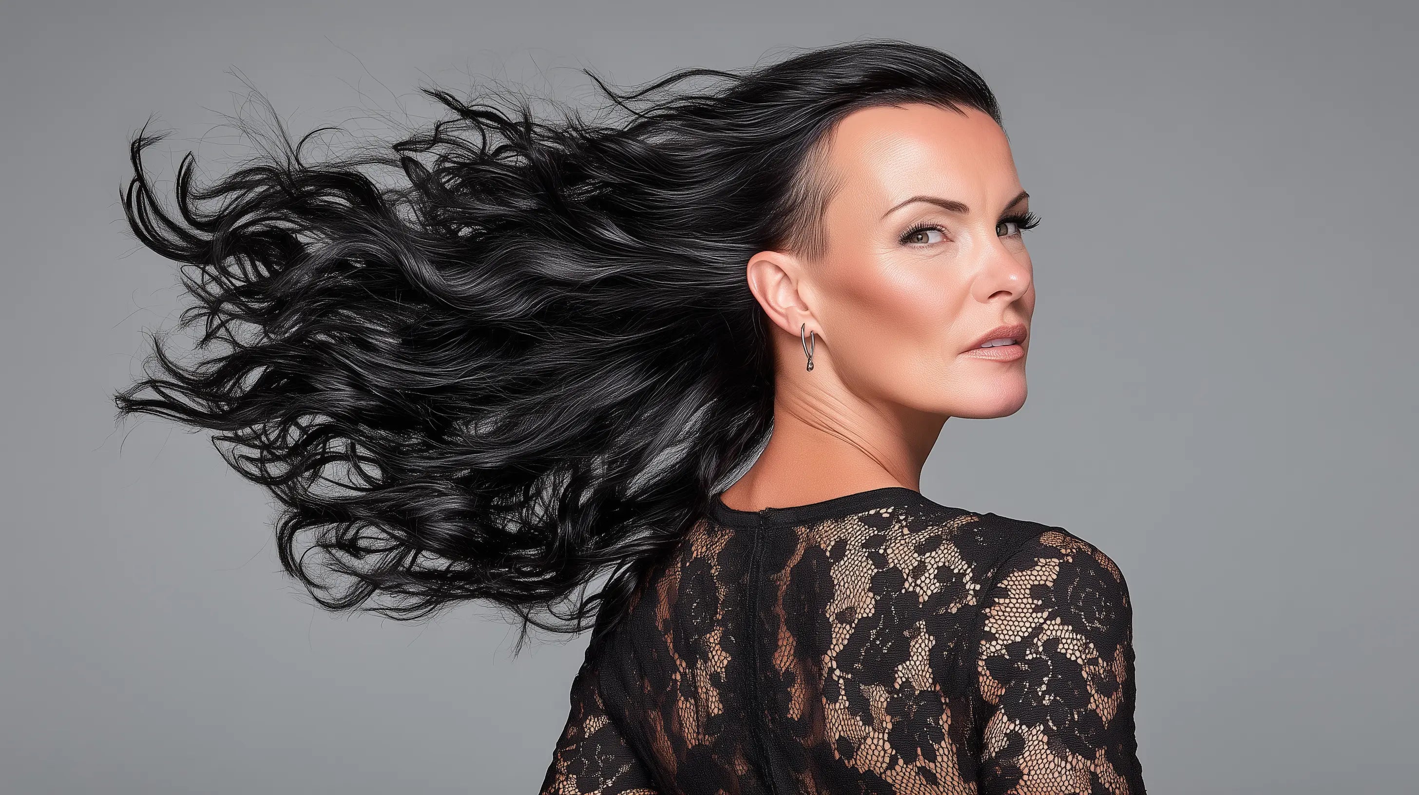 Woman with flowing black hair against a gray background