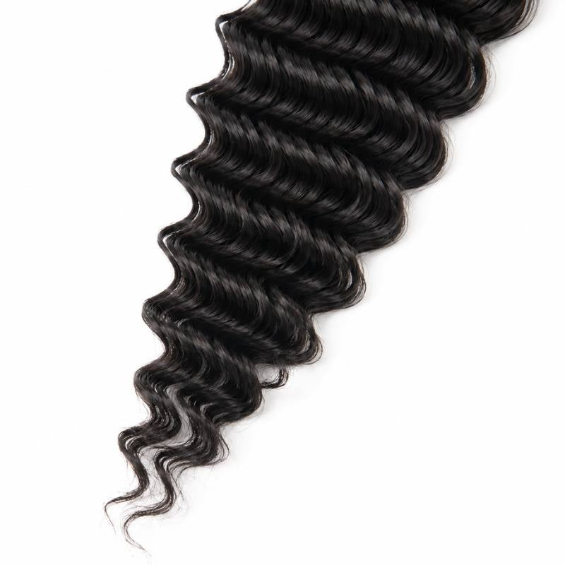 Close-up of the tapering wave ends on natural black deep wave sew-in hair extensions on a white background