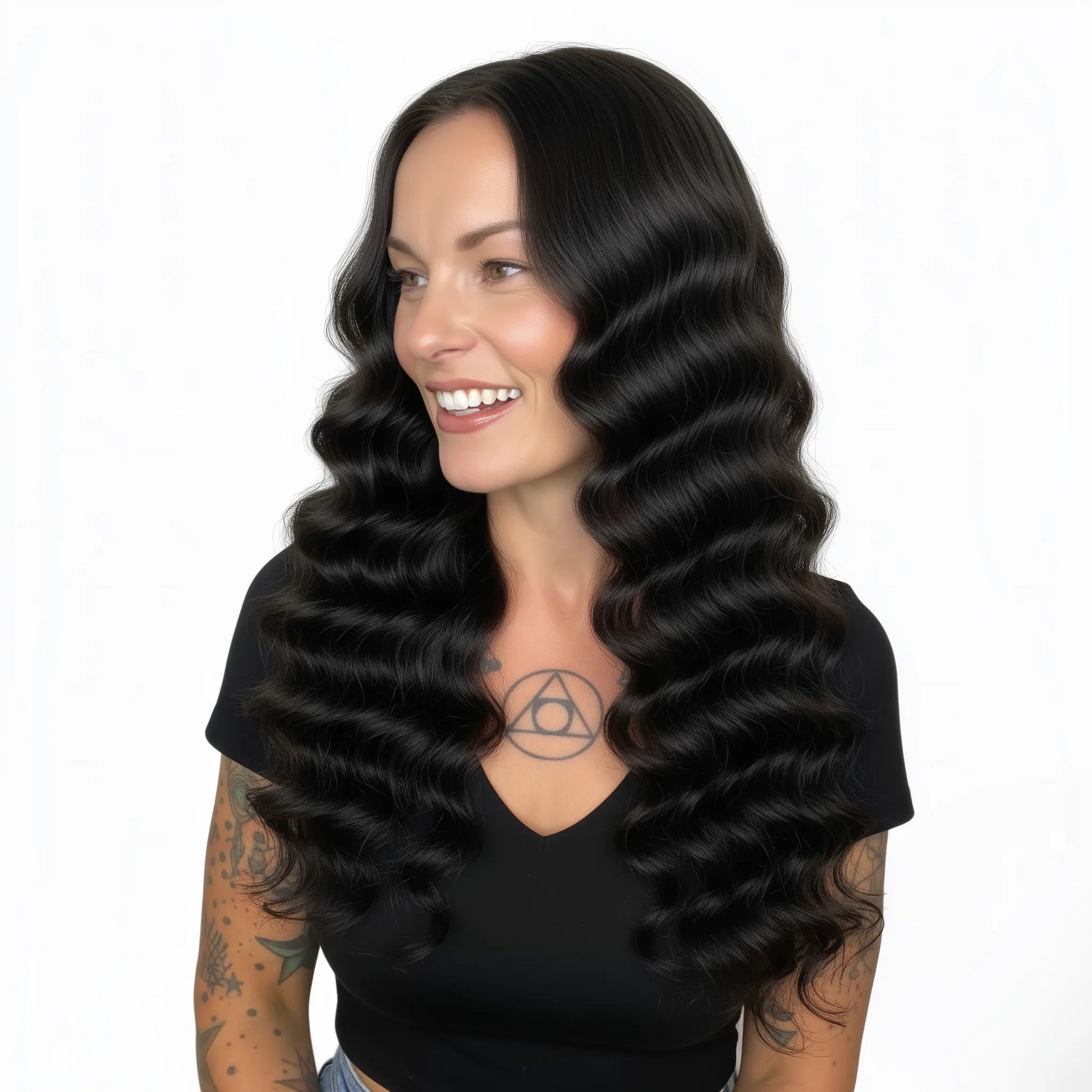 Woman with long, wavy black hair wearing a black top on a white background