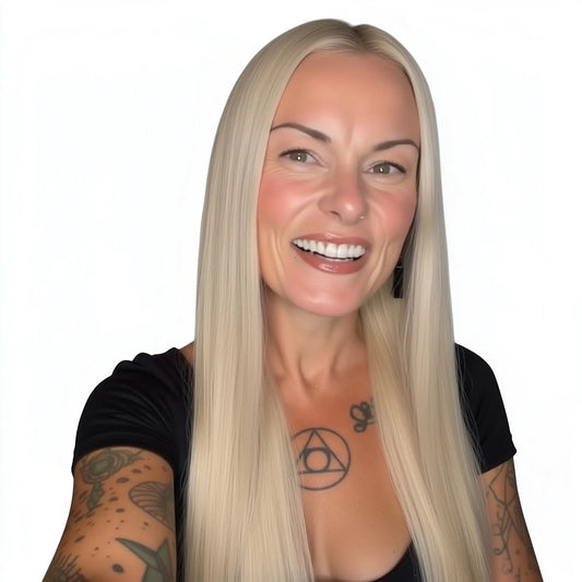 Woman with long blonde hair and tattoos on arms against a white background