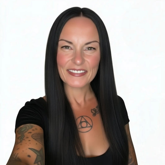 Woman with long black hair and tattoos on arms against a white background