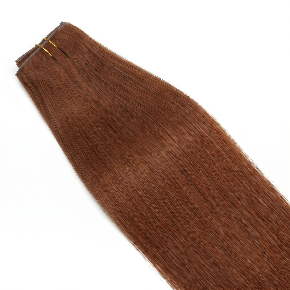 Copper straight clip-in hair extensions laid flat and tied with gold thread showing the weft top and the smooth tapered lengths