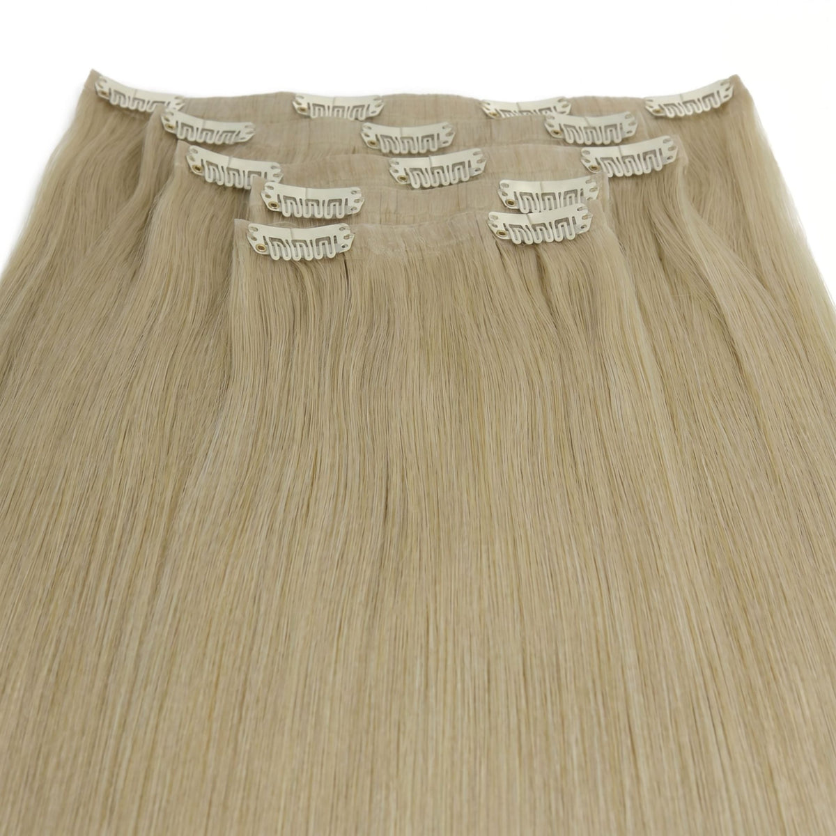 Full set of honey blonde straight clip-in hair extensions laid flat with pale snap clips stitched along each seamless band