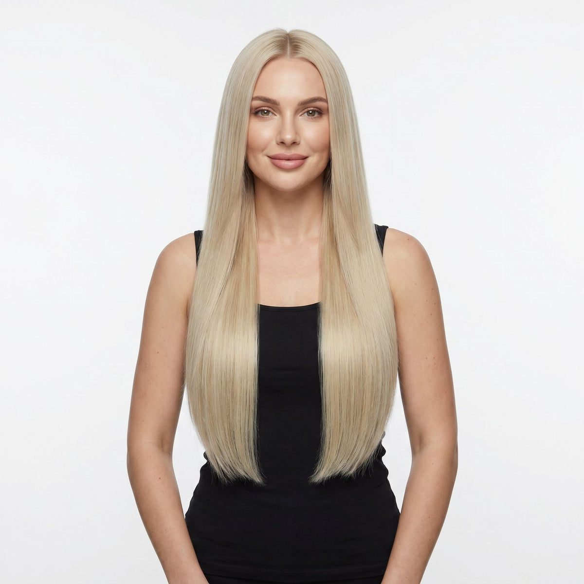 Model facing forward wearing long straight honey blonde clip-in hair extensions parted in the centre against a white studio backdrop