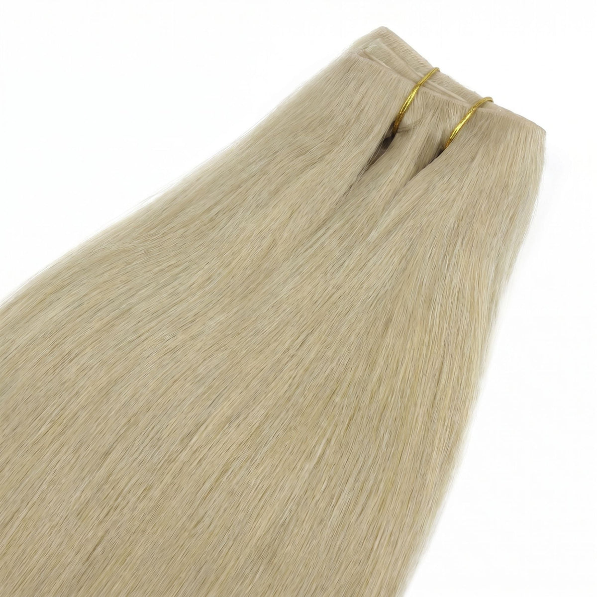 Honey blonde straight clip-in hair extensions laid flat and tied with gold thread showing the weft top and the tapered lengths