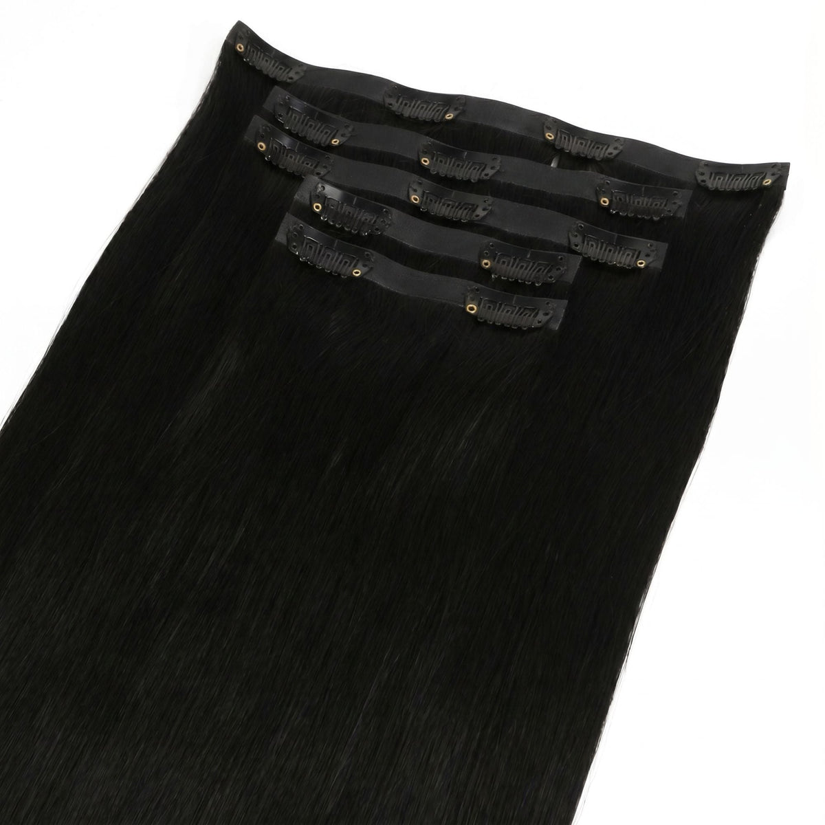 Close-up of the black snap clips and thin bands stitched onto jet black straight clip-in hair extensions laid on a white surface