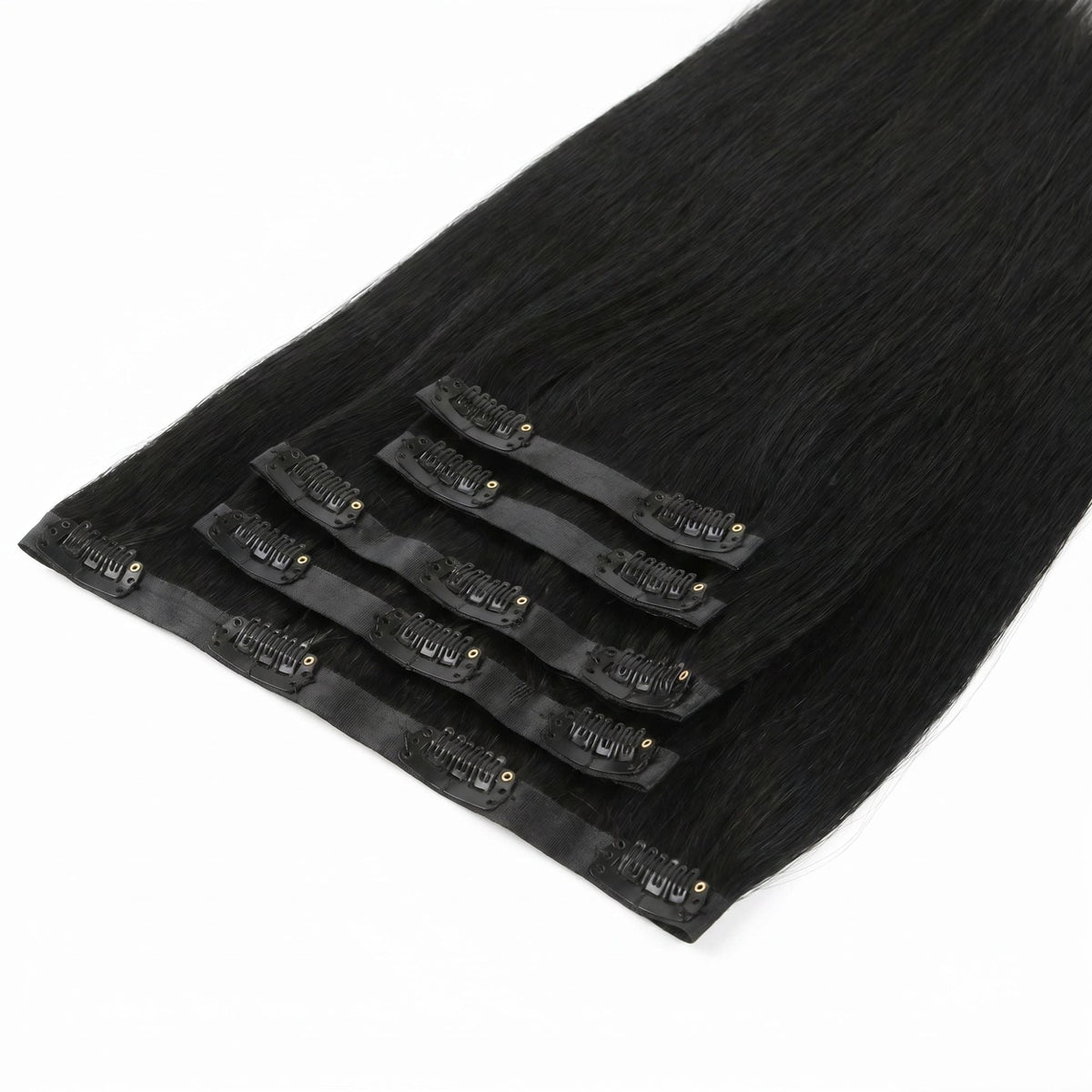 Jet black straight clip-in hair extensions stacked on a diagonal with the clipped seamless bands running through the middle