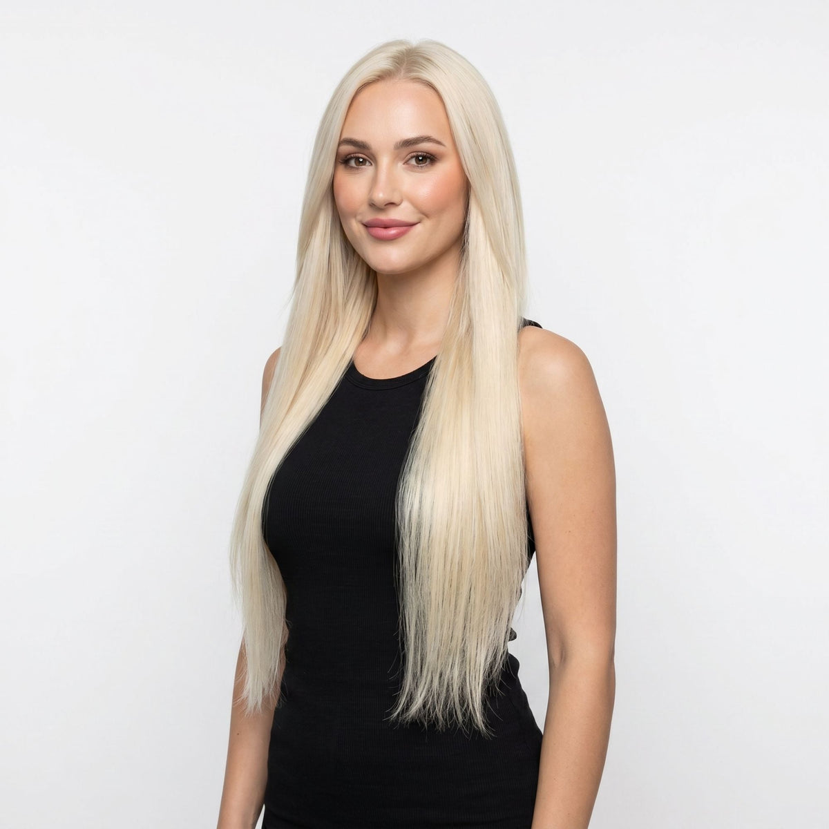 Model in a black top wearing long straight platinum blonde clip-in hair extensions with a centre part against a white background