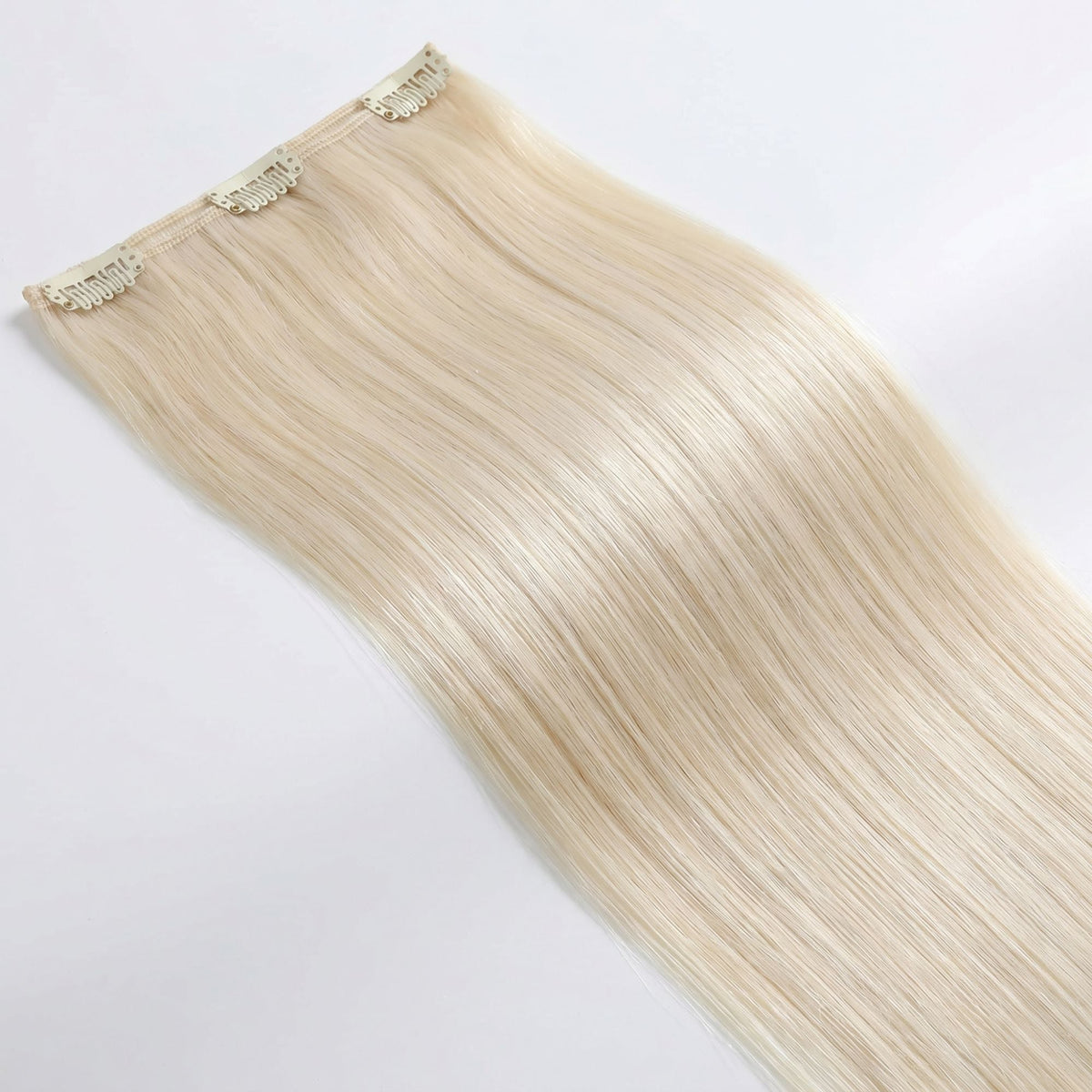 Single wide weft of platinum blonde straight clip-in hair extensions laid flat with three snap clips along the stitched top edge