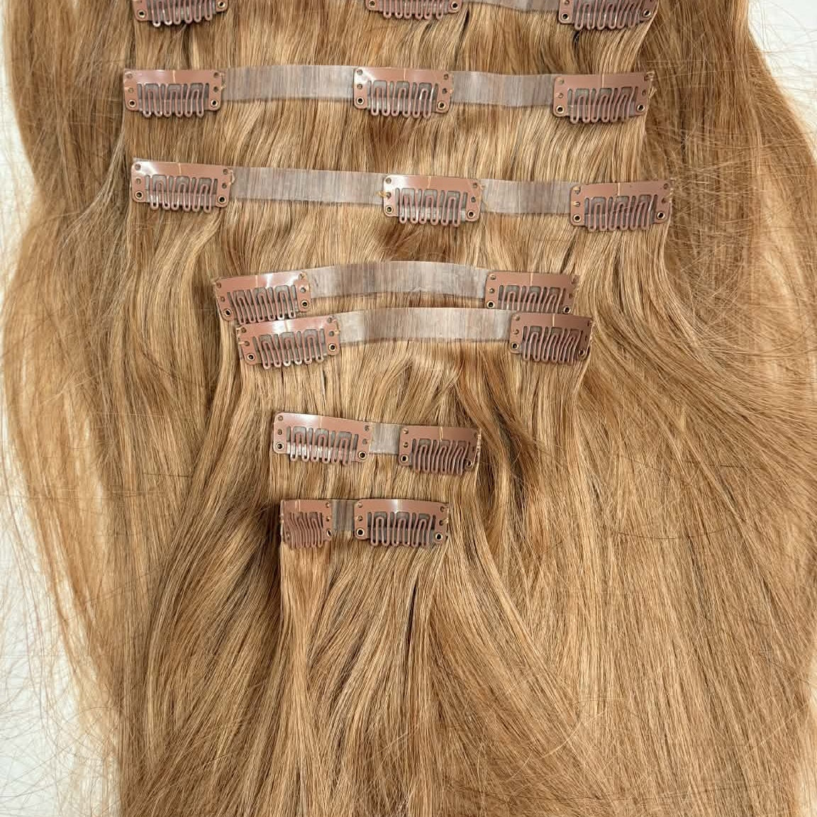 Full layout of 20 inch honey blonde 27 seamless clip-in hair extension set showing all weft pieces with clips attached