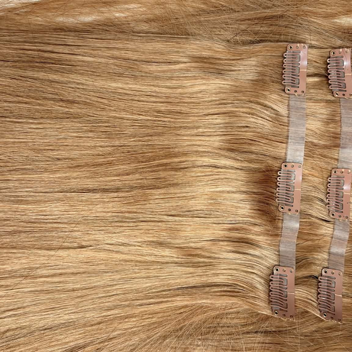 Close-up of 20 inch honey blonde seamless clip-in hair extension weft showing straight hair texture and PU seamless edge