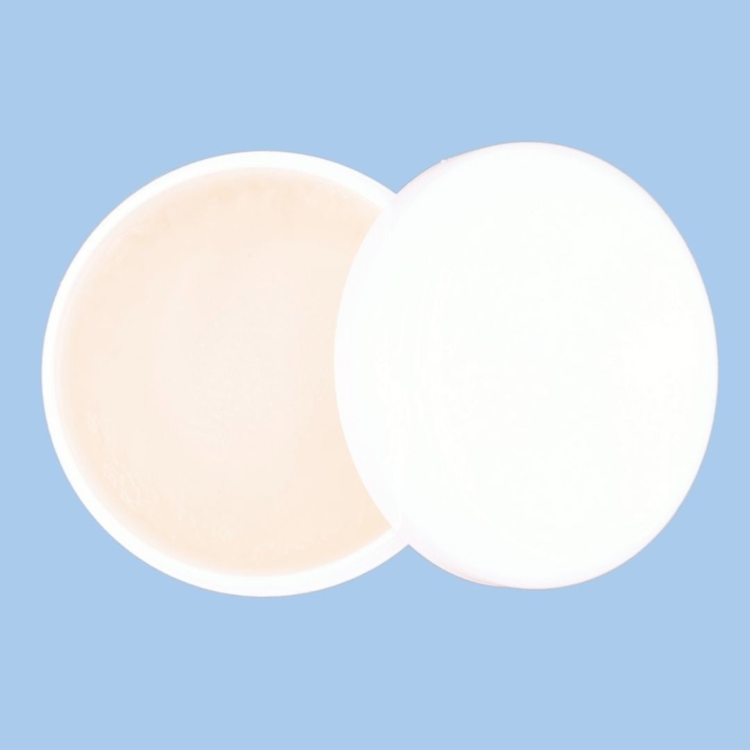 Overhead shot of an open edge control jar with its lid overlapping on a pale blue backdrop, the gel used for edges with hair extensions