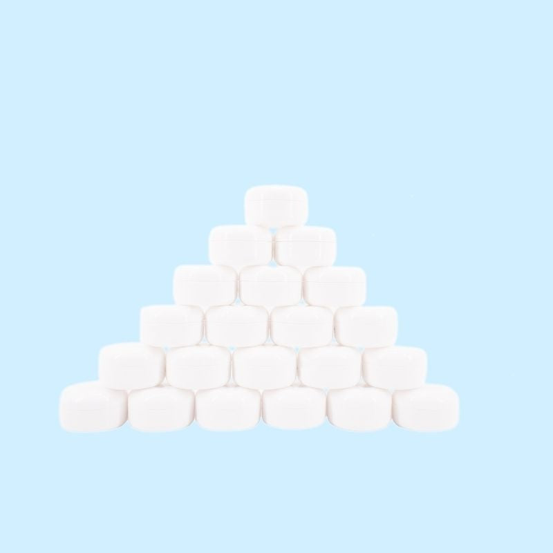 Closed white edge control jars stacked in a pyramid on a pale blue backdrop, a styling gel stocked alongside hair extensions