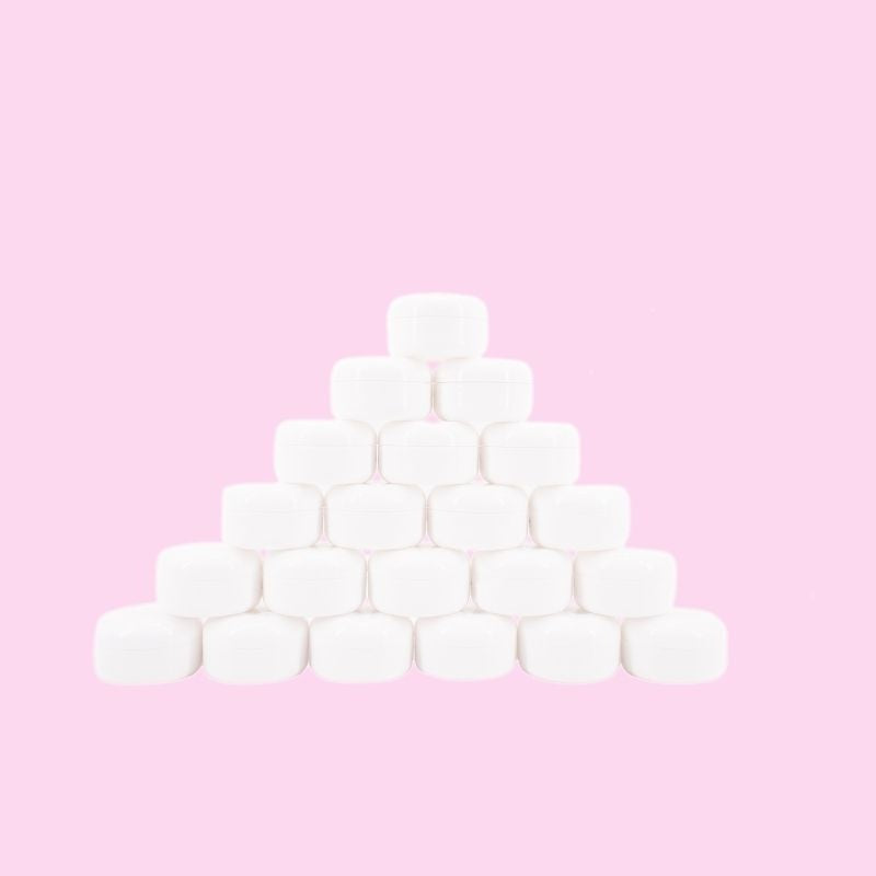 Closed white edge control jars stacked in a pyramid on a pink backdrop, a styling gel stocked alongside hair extensions