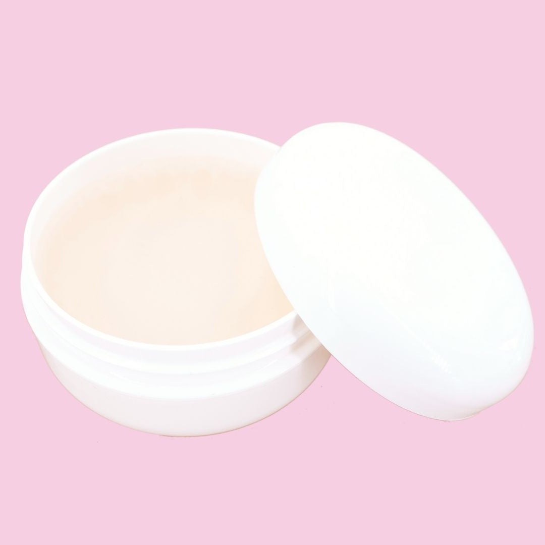 Open edge control jar with the lid leaning against it on a pink backdrop, showing the cream gel used for edges with hair extensions