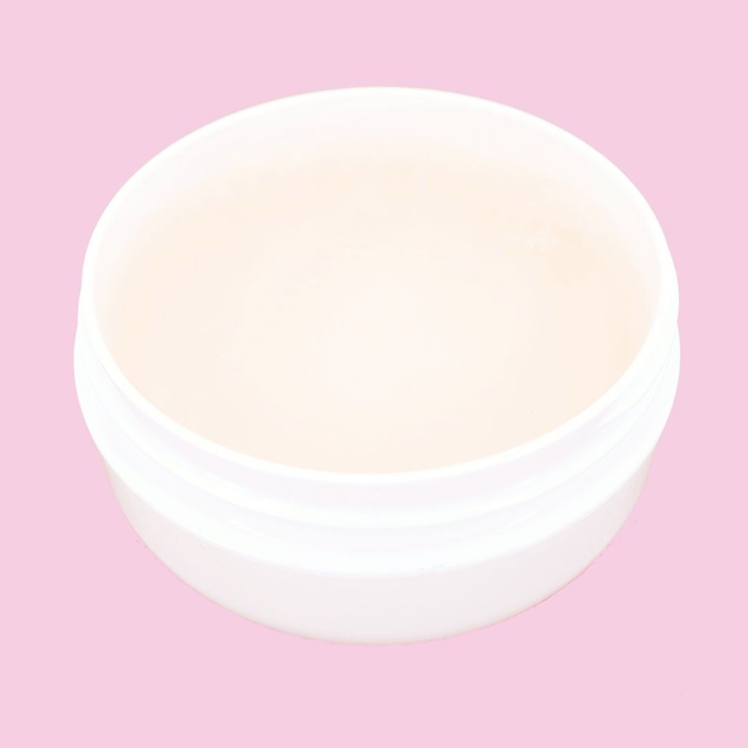 Open edge control jar photographed from above on a pink backdrop, showing the smooth cream gel used when laying edges with hair extensions