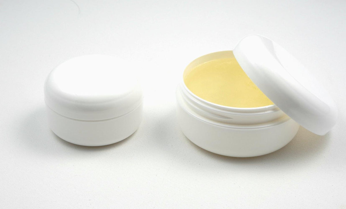 Two white edge control jars side by side, one closed and one open revealing the pale yellow gel used when styling hair extensions