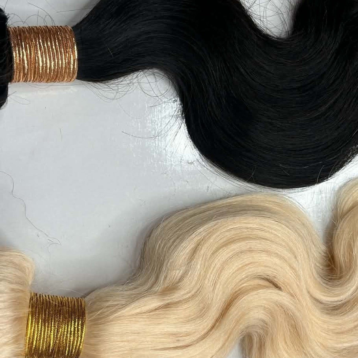 Two body-wave bundles flat-laid side by side, one natural black and one blonde, machine wefts showing, with a purple x3 deal badge in the corner