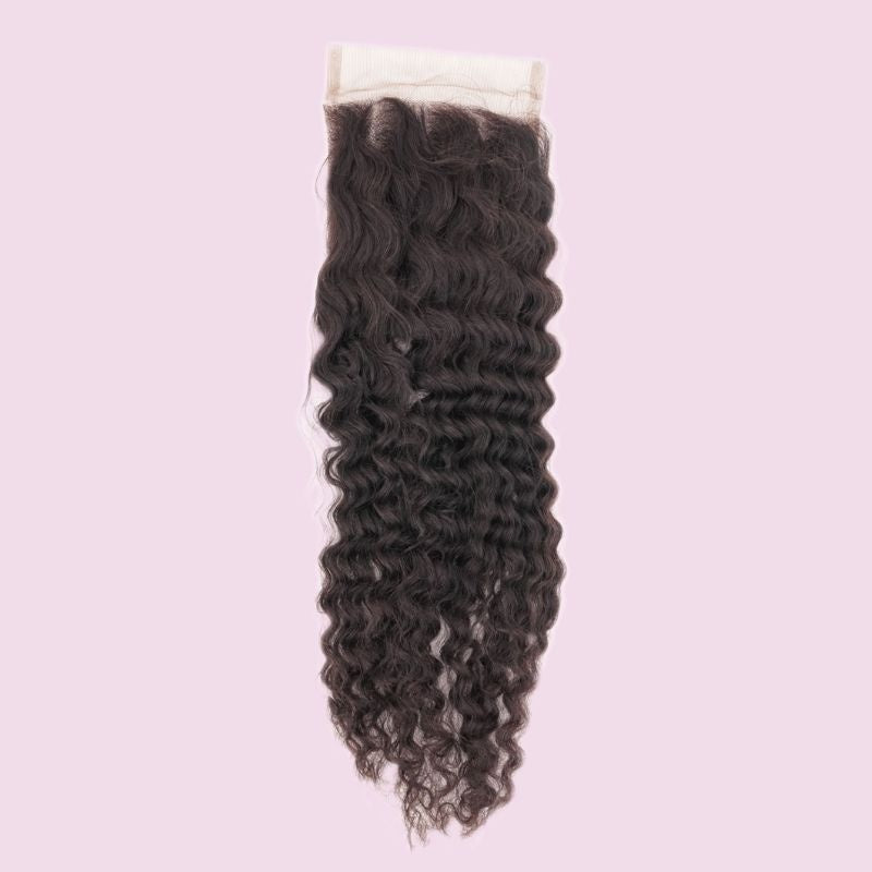 Transparent lace closure with natural black curly hair extensions photographed against a pale pink backdrop
