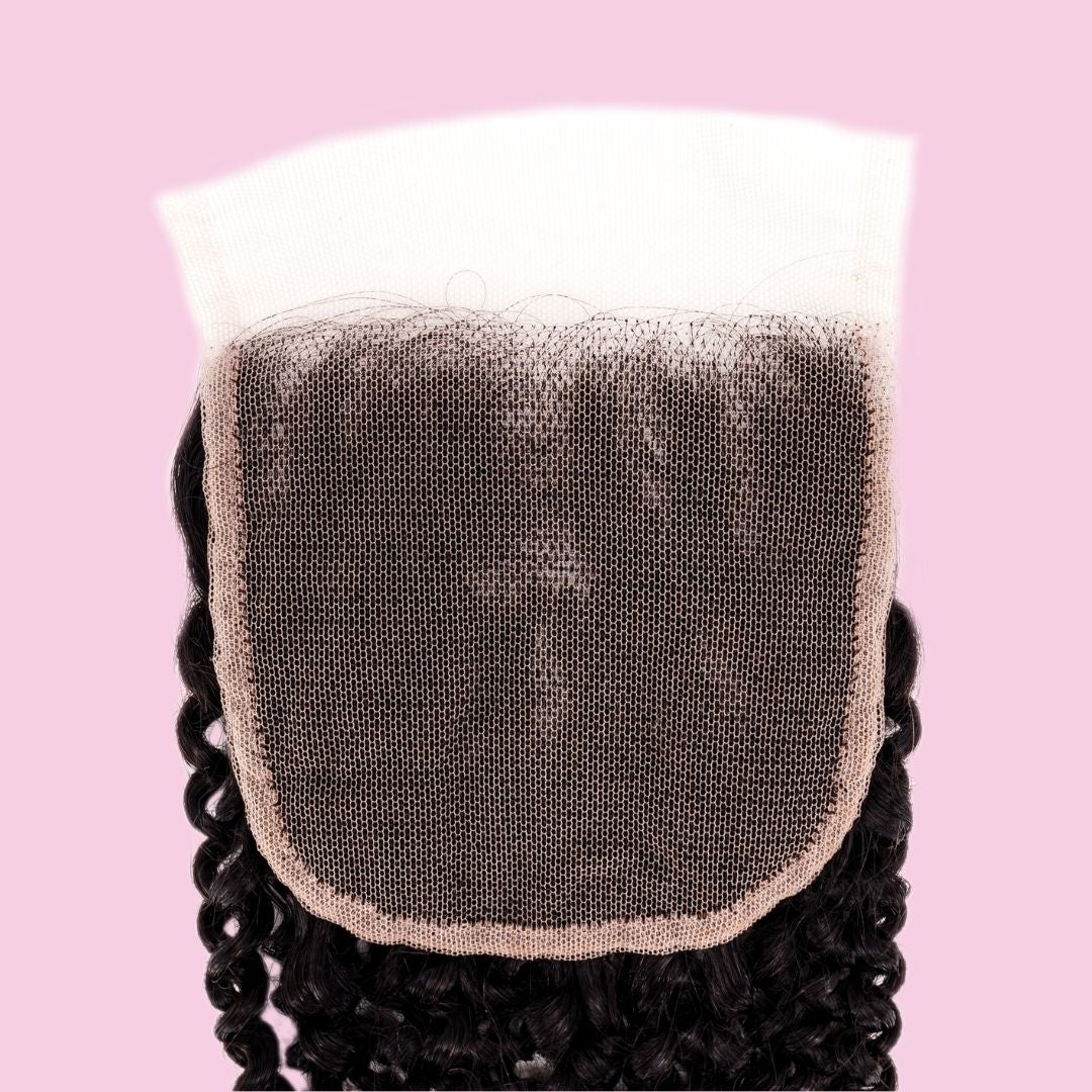Close-up of the transparent lace panel on a pink backdrop, with natural black curly hair extensions knotted around its edge