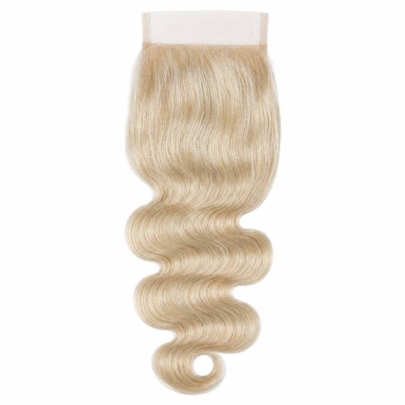 Blonde body wave hair extensions on a square transparent lace closure hanging against a white background with an S shaped wave pattern