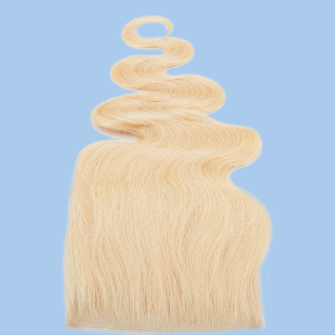 Blonde body wave hair extensions with the ends fanned wide and a wave curling above, shown against a pale blue backdrop
