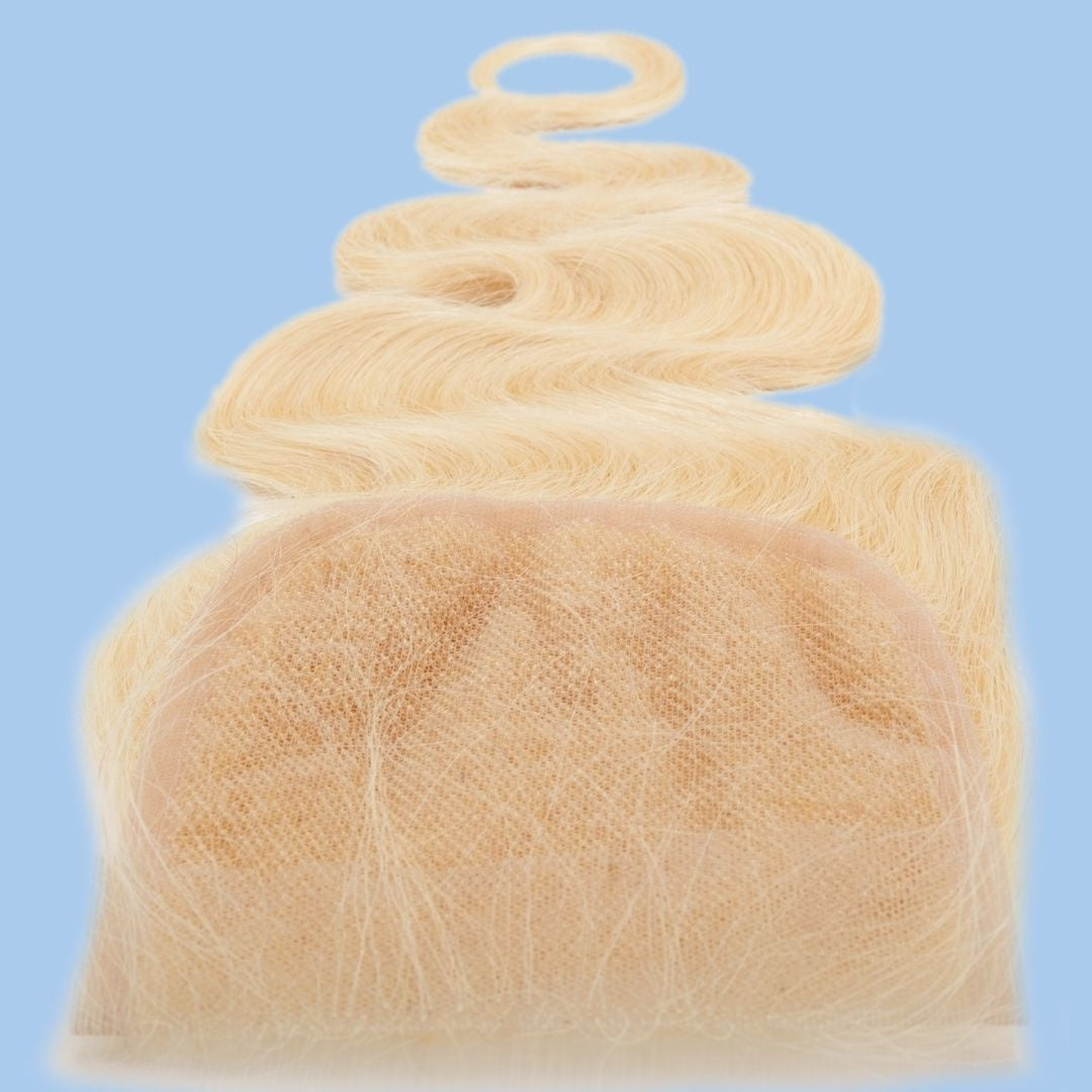 Close-up of the transparent lace panel on a blonde body wave hair extensions closure against a blue backdrop with the wave lying above