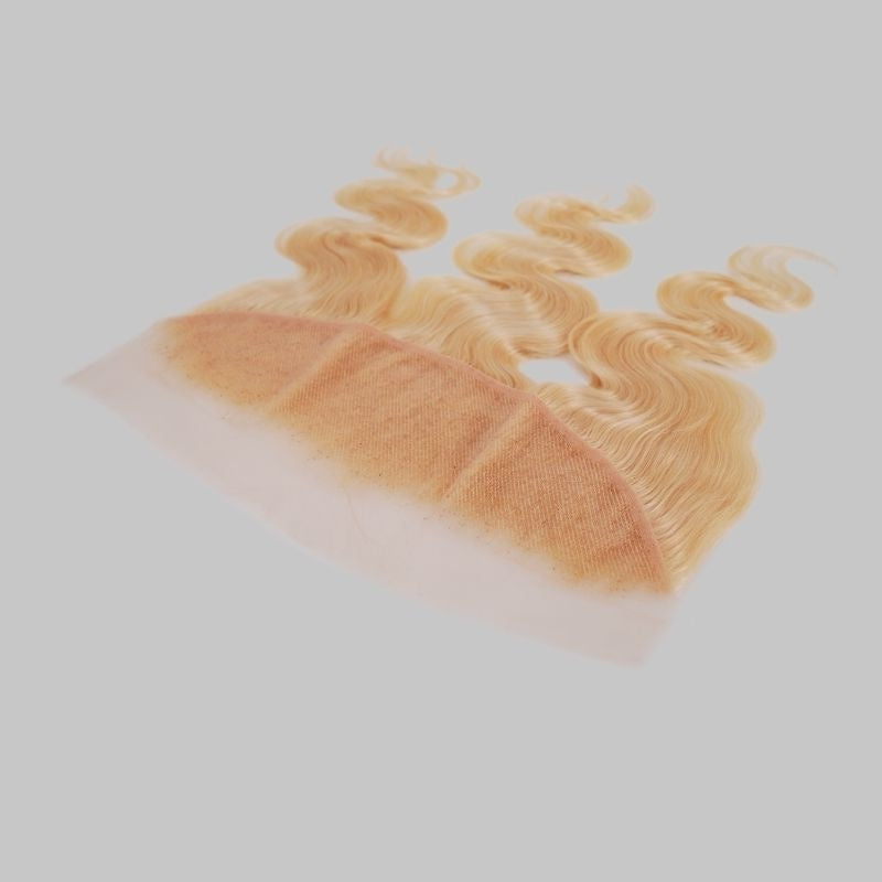 Blonde 613 body wave transparent frontal tilted on a grey background to show the lace base and the parting seams of the hair extensions