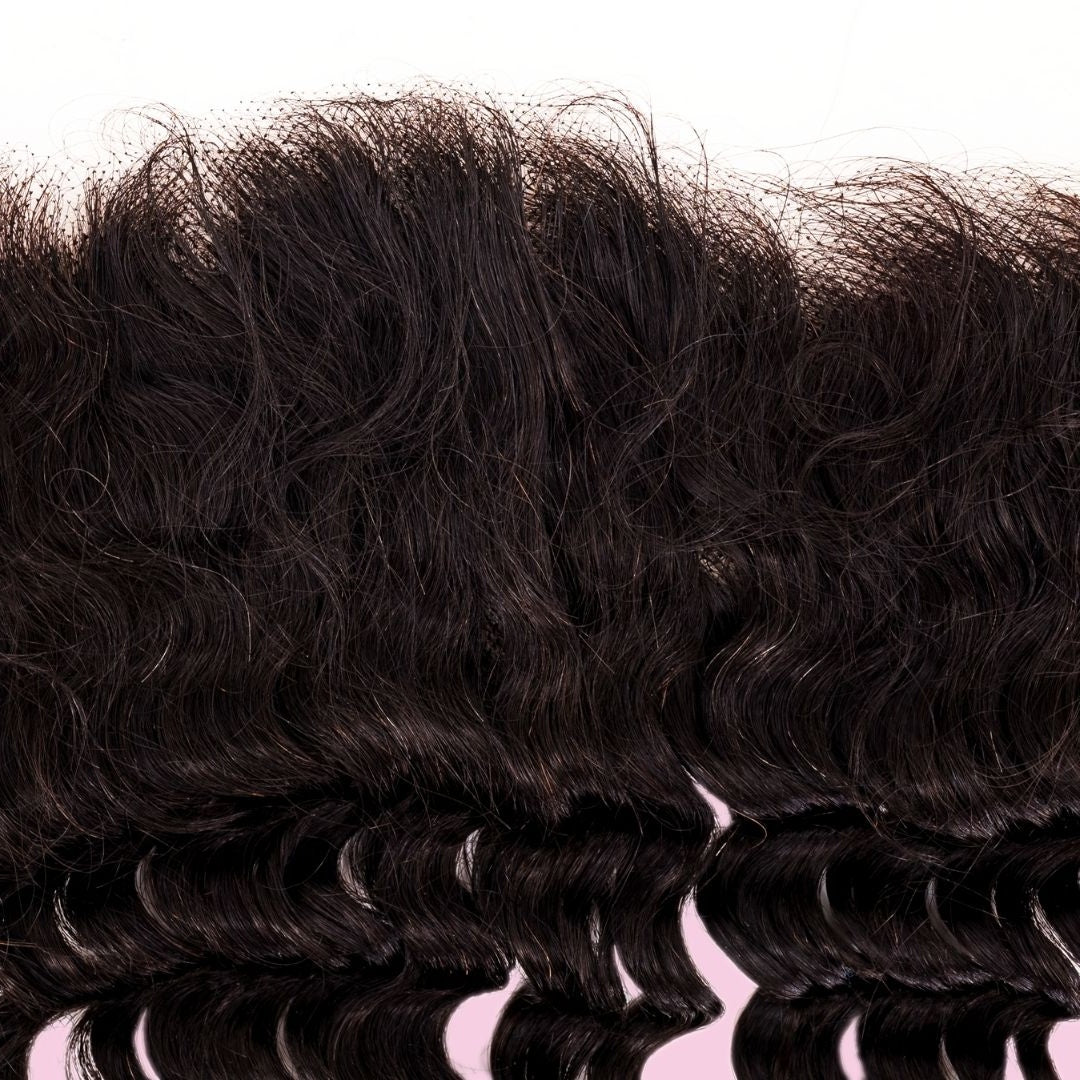 Tight close-up of the roots and curl definition on the natural black deep wave hair extensions of the transparent frontal