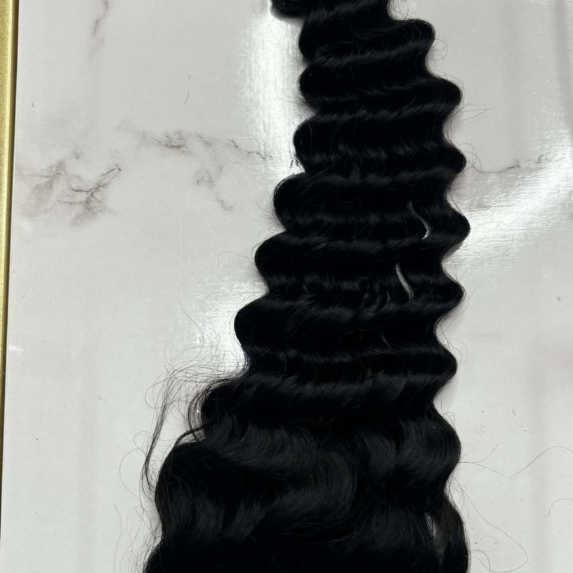 16 inch Brazilian deep wave 4x4 transparent closure hair extension flat lay on marble surface showing lace parting and curl definition