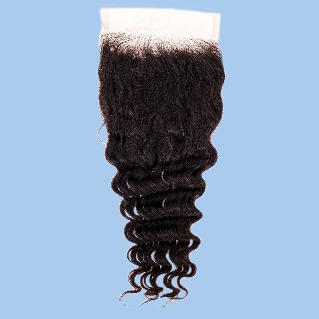 Natural black 4x4 transparent closure on a blue background showing the lace band at the top and the curl of the deep wave hair extensions