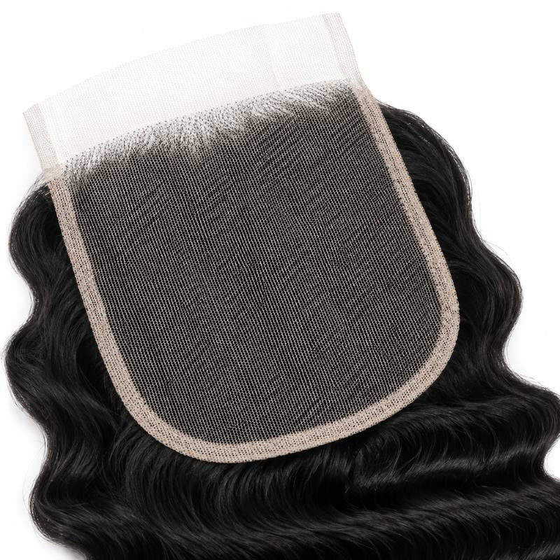Close-up of the square lace panel and bound edge on a natural black 4x4 transparent closure with deep wave hair extensions around it