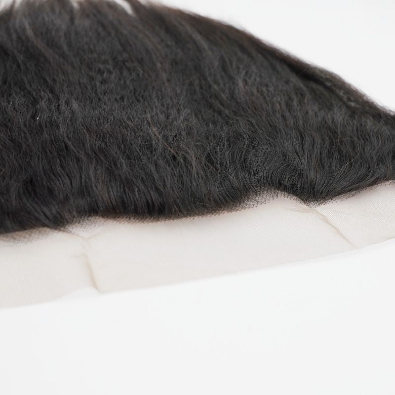 Low angle across the lace hairline of a natural black kinky straight transparent frontal with the hair extensions lying over the lace panel