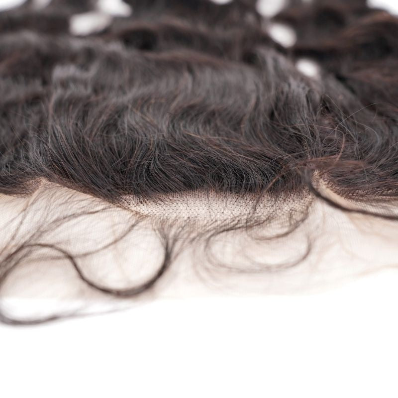Macro close-up of the frontal hairline showing knots along the transparent lace and stray baby hairs on natural black loose wave hair extensions