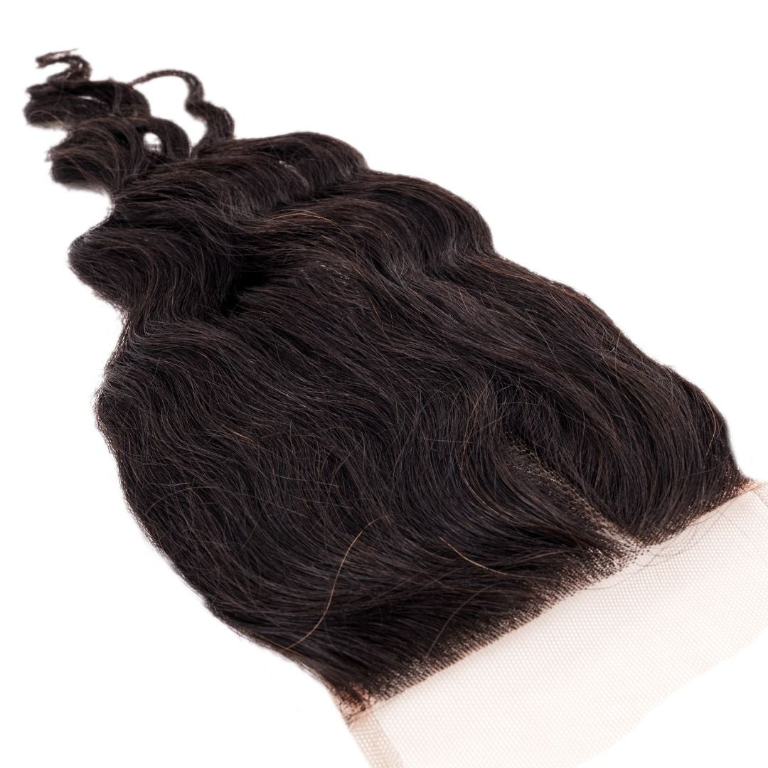 Angled close-up of the closure showing a corner of the transparent lace and the wave texture of natural black loose wave hair extensions