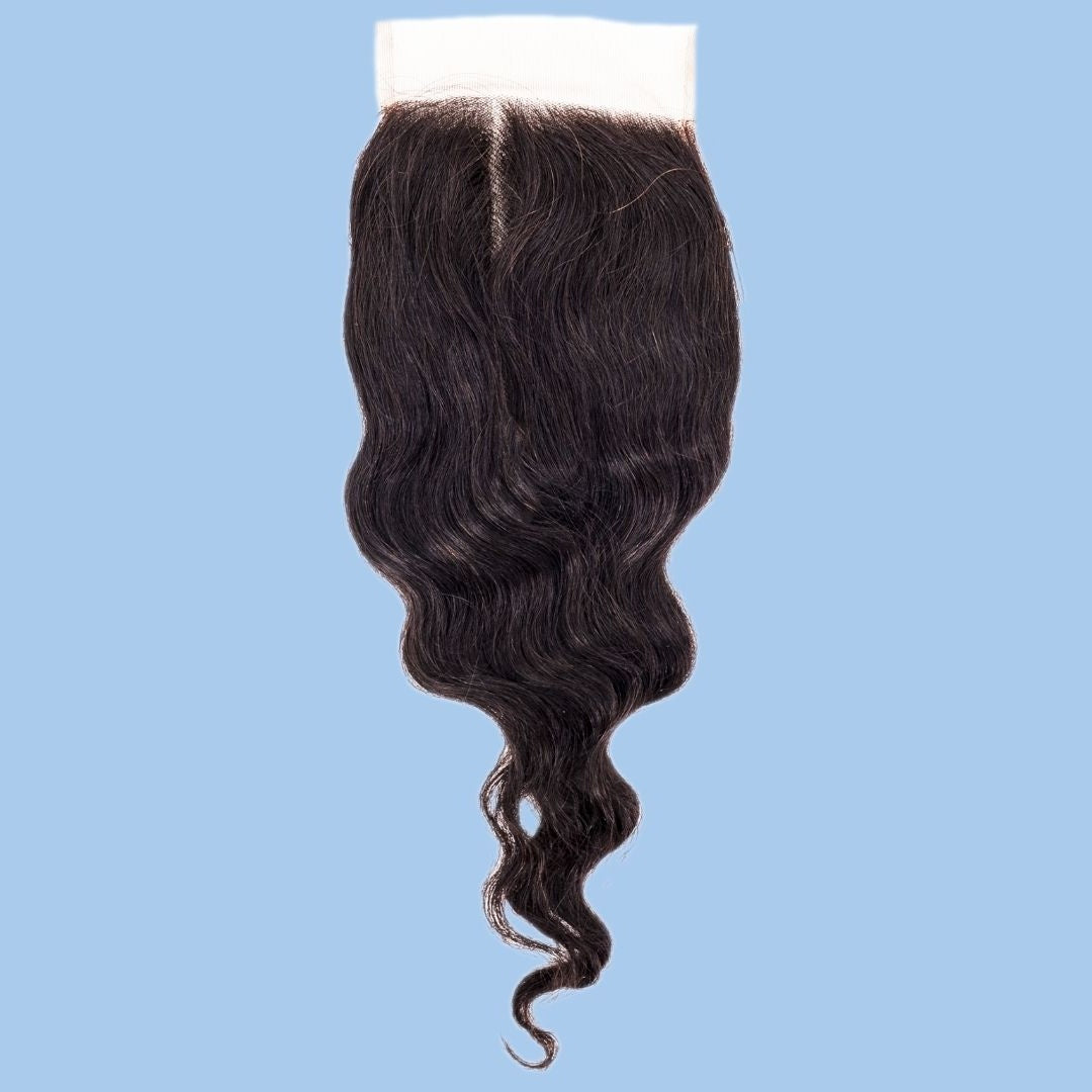4x4 transparent closure on a blue background showing the middle part and wave pattern of natural black loose wave hair extensions