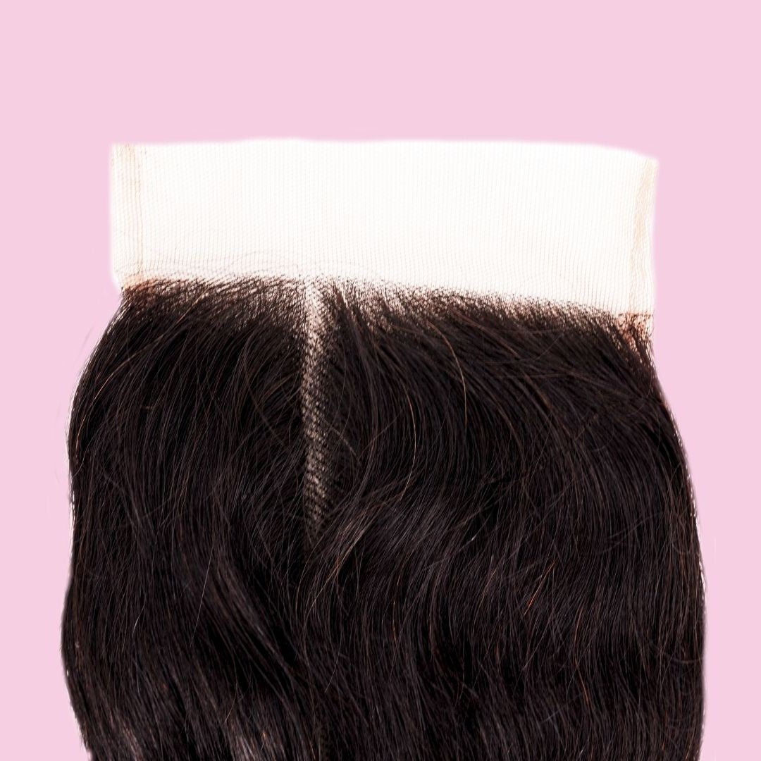 Close-up of the middle parting and transparent lace band on natural black loose wave hair extensions against a pink background
