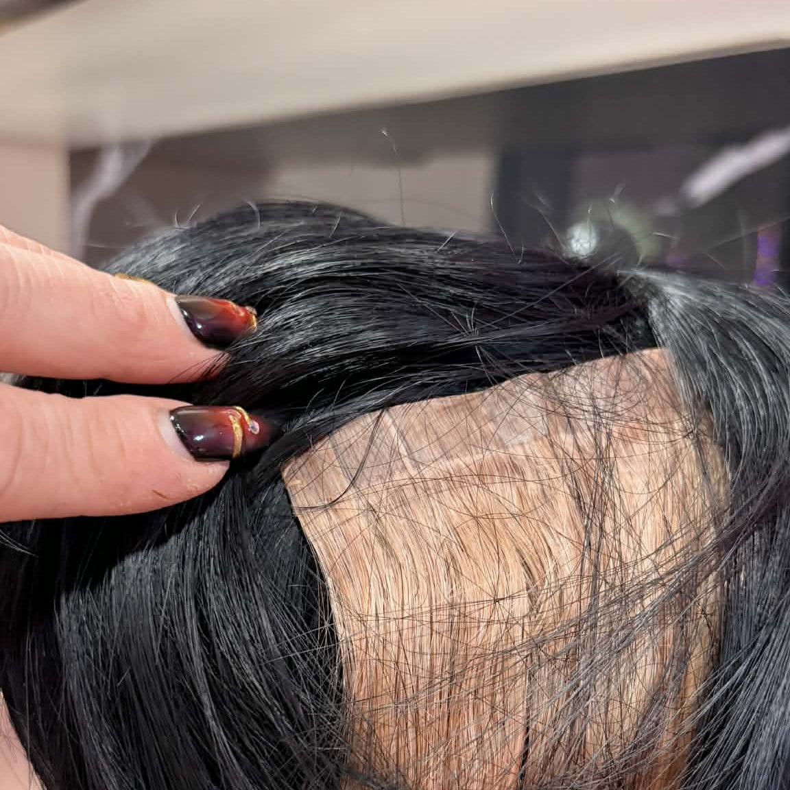 Hand holding 14 inch Brazilian straight 5x5 HD closure hair extension showing lace base construction and straight hair texture