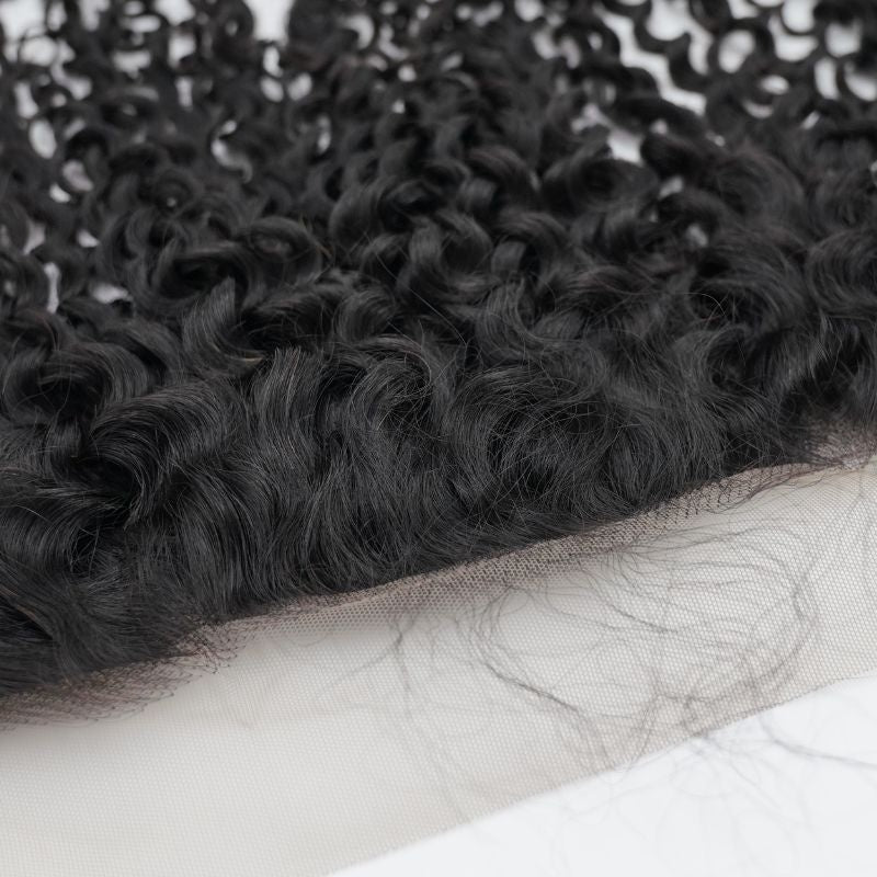 Close-up of the hairline where natural black kinky curly hair extensions meet the transparent lace with fine hairs along the edge