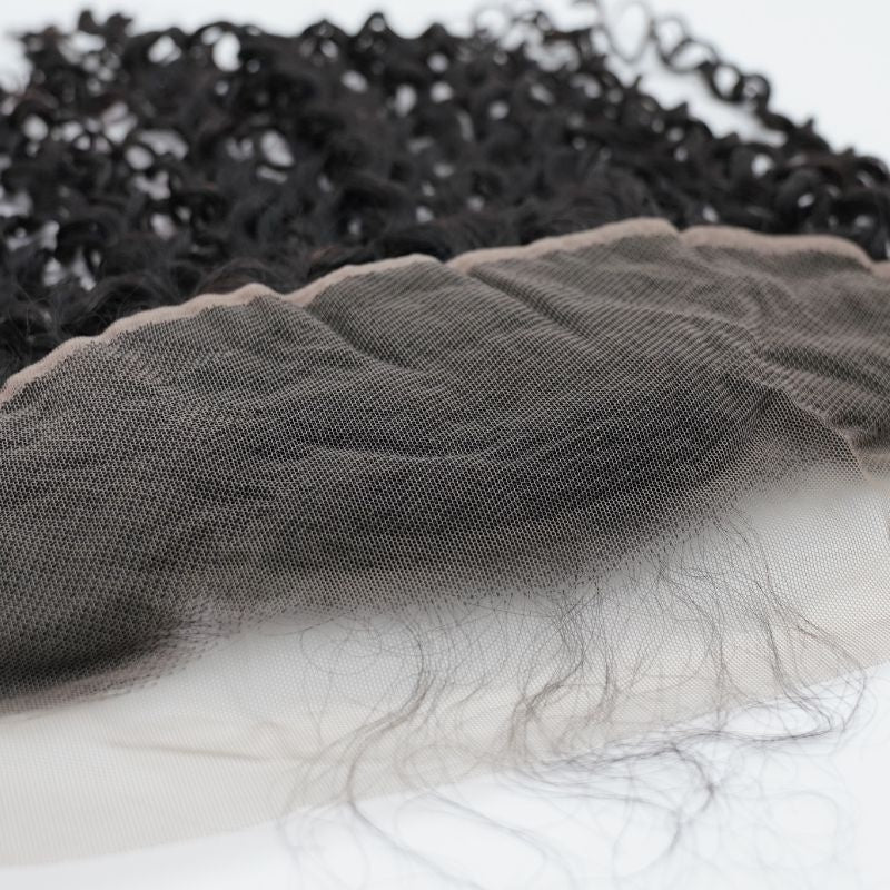 Macro view of the transparent lace mesh and knotted hairline on natural black kinky curly frontal hair extensions