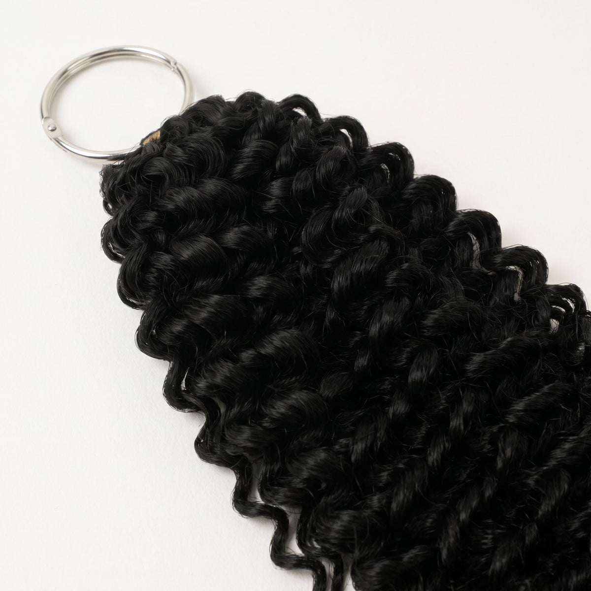 Natural black kinky curly feather crochet hair extensions shown from the ring end with the coiled curl pattern running down