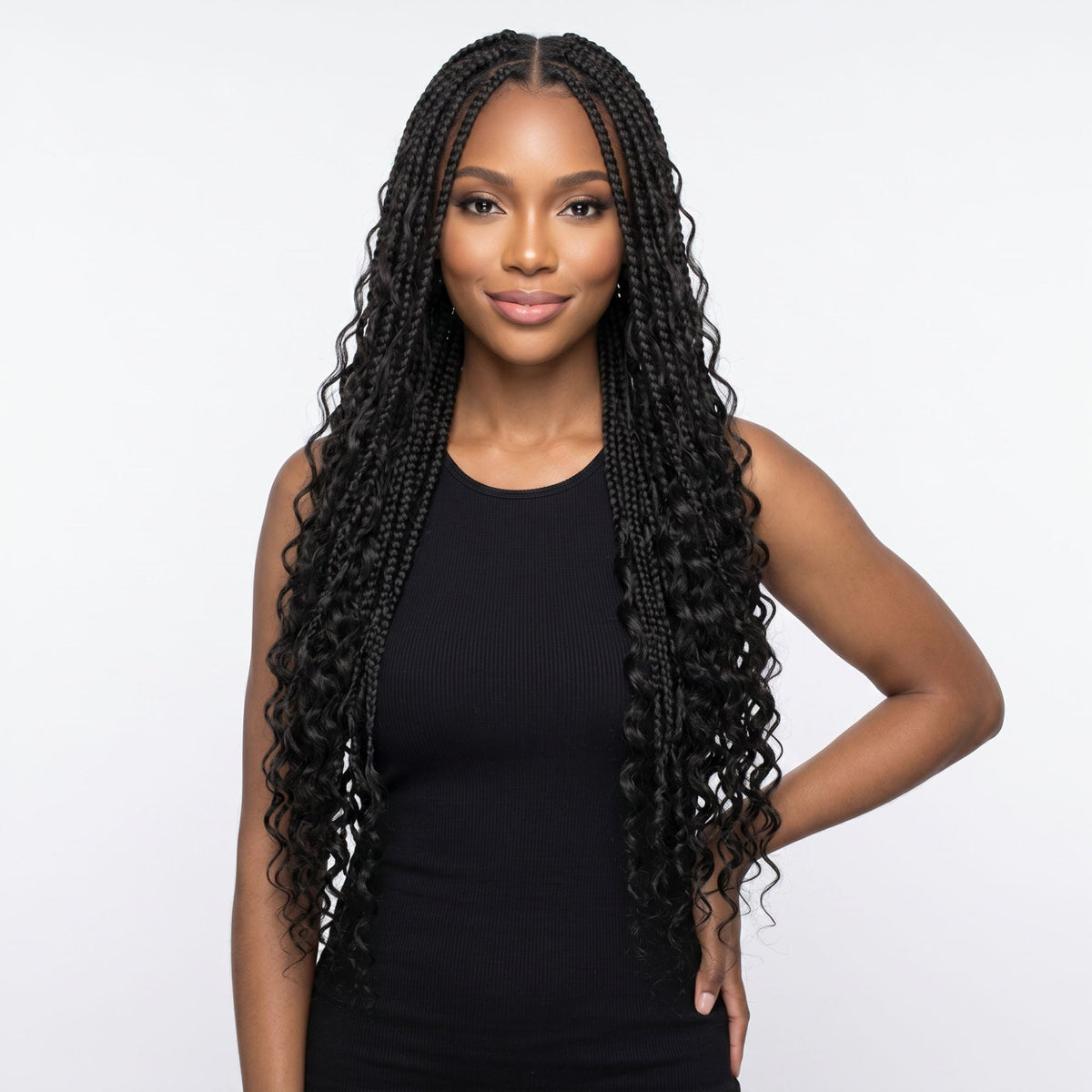 Model with a hand on her hip wearing long braids with curly ends in natural black bulk braiding hair extensions on a white background