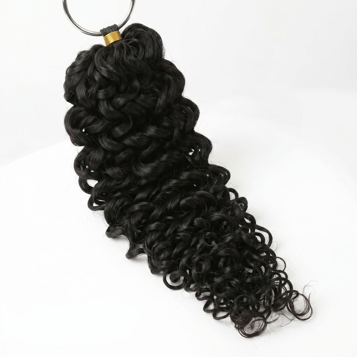 Natural black ocean wave crochet hair extensions hanging from a metal ring above the gold band binding the strands