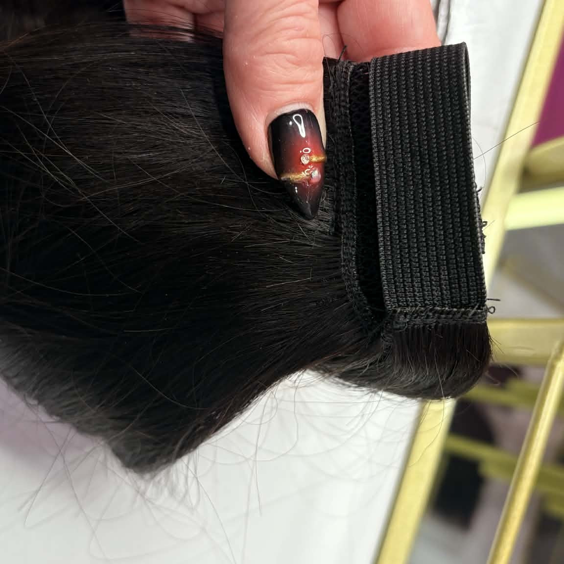 Close-up detail of wrap-around strap and velcro closure on 16 inch natural black ponytail hair extension