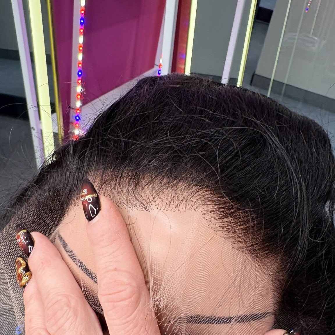 Hand holding 16 inch straight 13x4 HD lace frontal hair extension in natural black showing lace base construction and hair texture