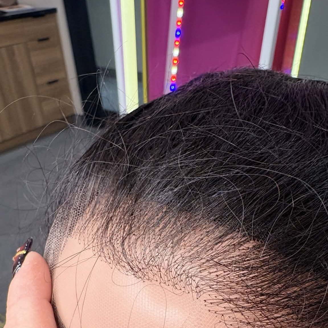 Close-up of 13x4 HD lace frontal hair extension in natural black on mannequin head showing transparent lace grid and straight hair parting