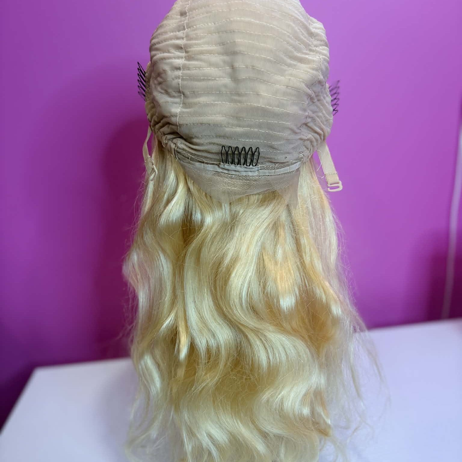 Interior back cap detail of 16 inch blonde body wave lace front human hair wig showing combs and elastic band