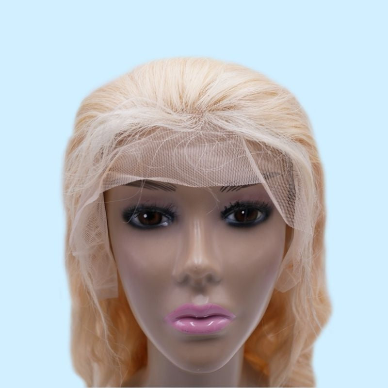 Front view of a blonde body wave human hair wig on a mannequin head against a pale blue backdrop with the lace still uncut