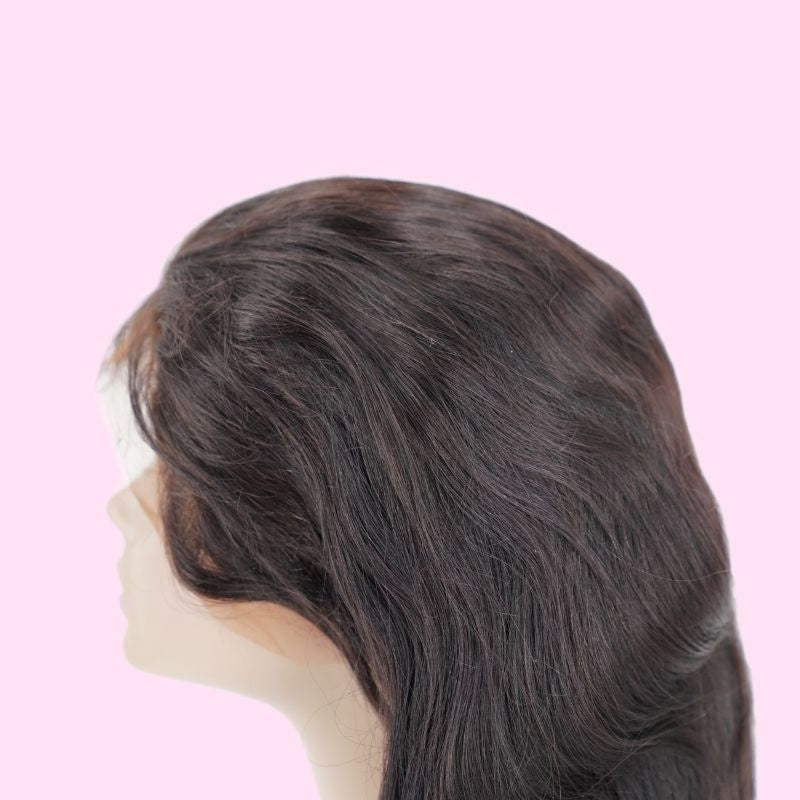 Body wave natural black human hair wig on a mannequin against pink showing the crown and the waved hair sweeping down the side