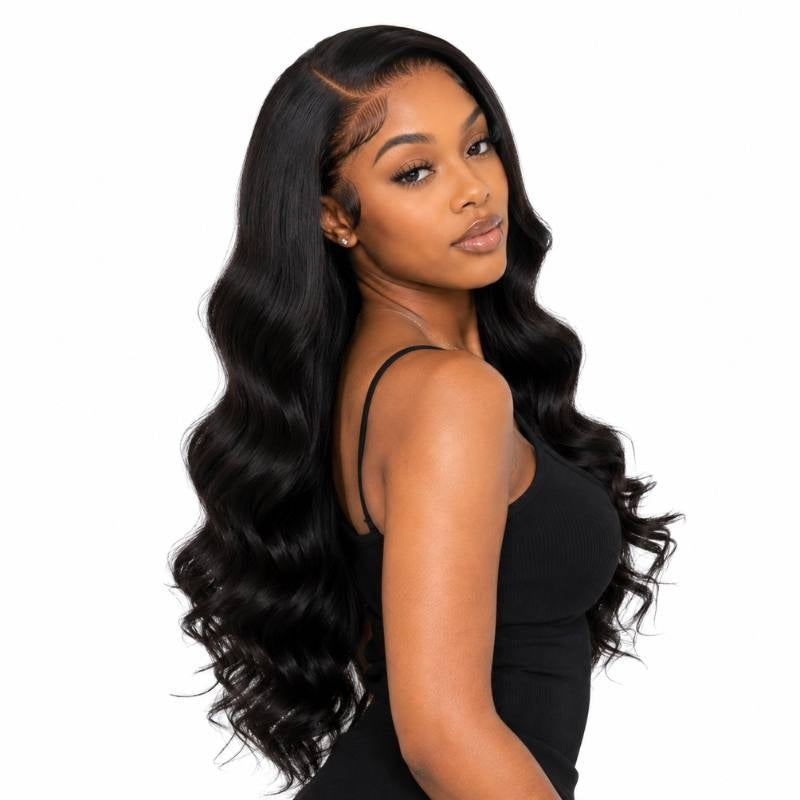 Model turning toward the camera wearing a long body wave natural black human hair wig with a deep side part and laid baby hairs